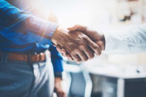 Image of a firm handshake, symbolizing the foundational importance of building and nurturing relationships in the commercial real estate industry. For brokers, cultivating genuine connections with investors often leads to sustained collaboration and growth, underscoring that genuine rapport transcends monetary gains