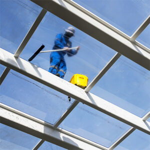 Person cleaning glass ceiling of commercial real estate property, following California property management law