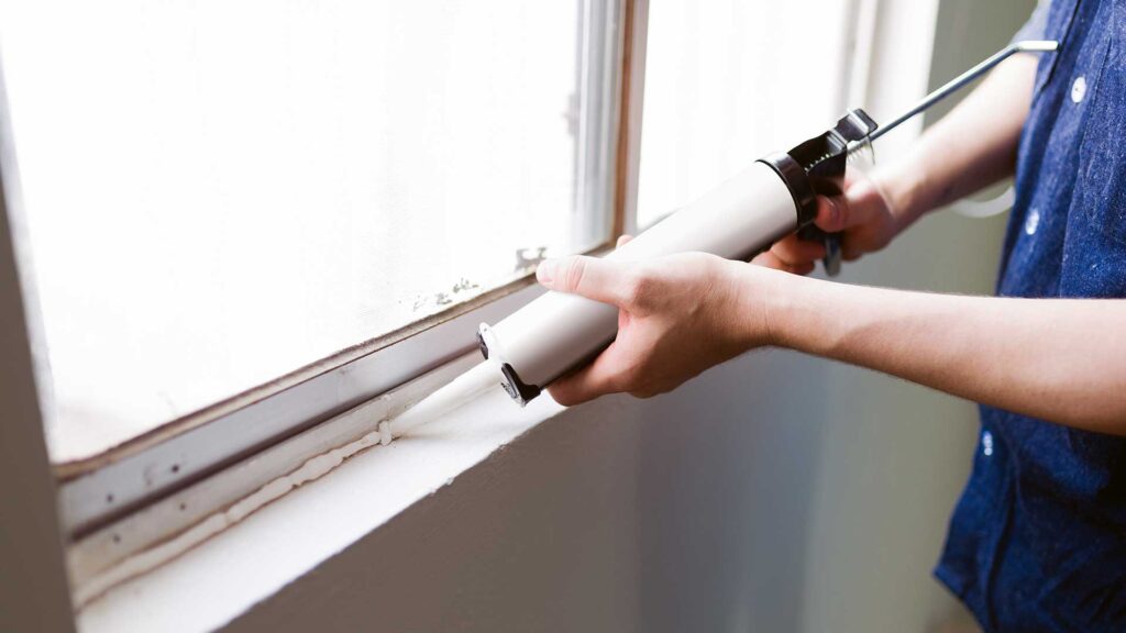 Worker sealing window frames while preparing your property for the winter season