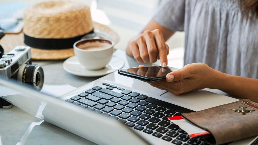 Traveler planning a trip on mobile device and laptop, representing AI search optimization for tourism and AI-powered travel planning