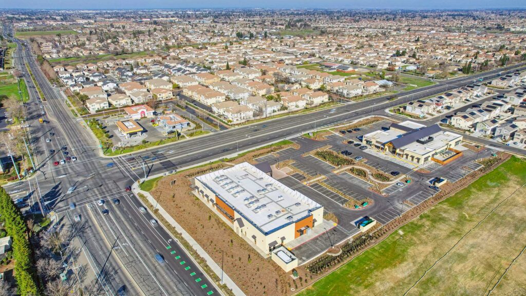 Aerial view of a PACE site selection location at a major intersection, surrounded by residential neighborhoods, commercial development, parking, and nearby transportation routes.
