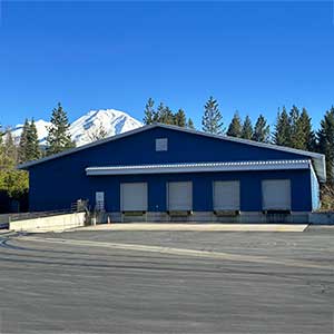 Northern California commercial real estate market featuring an industrial warehouse with multiple loading docks and a mountain backdrop.