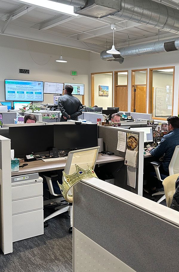 Group of brokers in the Capital Rivers office engaging in a professional discussion. The brokers, dressed in business attire, stand around a conference table, with the modern office environment visible in the background, including large windows and company branding. The handshake between two brokers represents collaboration and trust, while others in the group observe and contribute to the conversation. The scene emphasizes teamwork, professionalism, and successful tenant representation services within Capital Rivers.